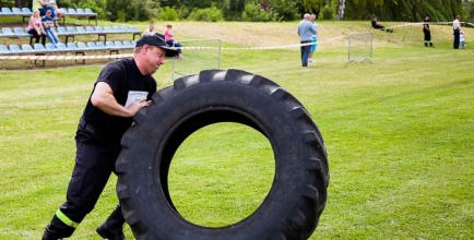 Zdjęcie z ubiegłorocznego Pikniku Sportowo - Strażackiego przedstawiające mężczyznę toczącego tylną oponę traktorową